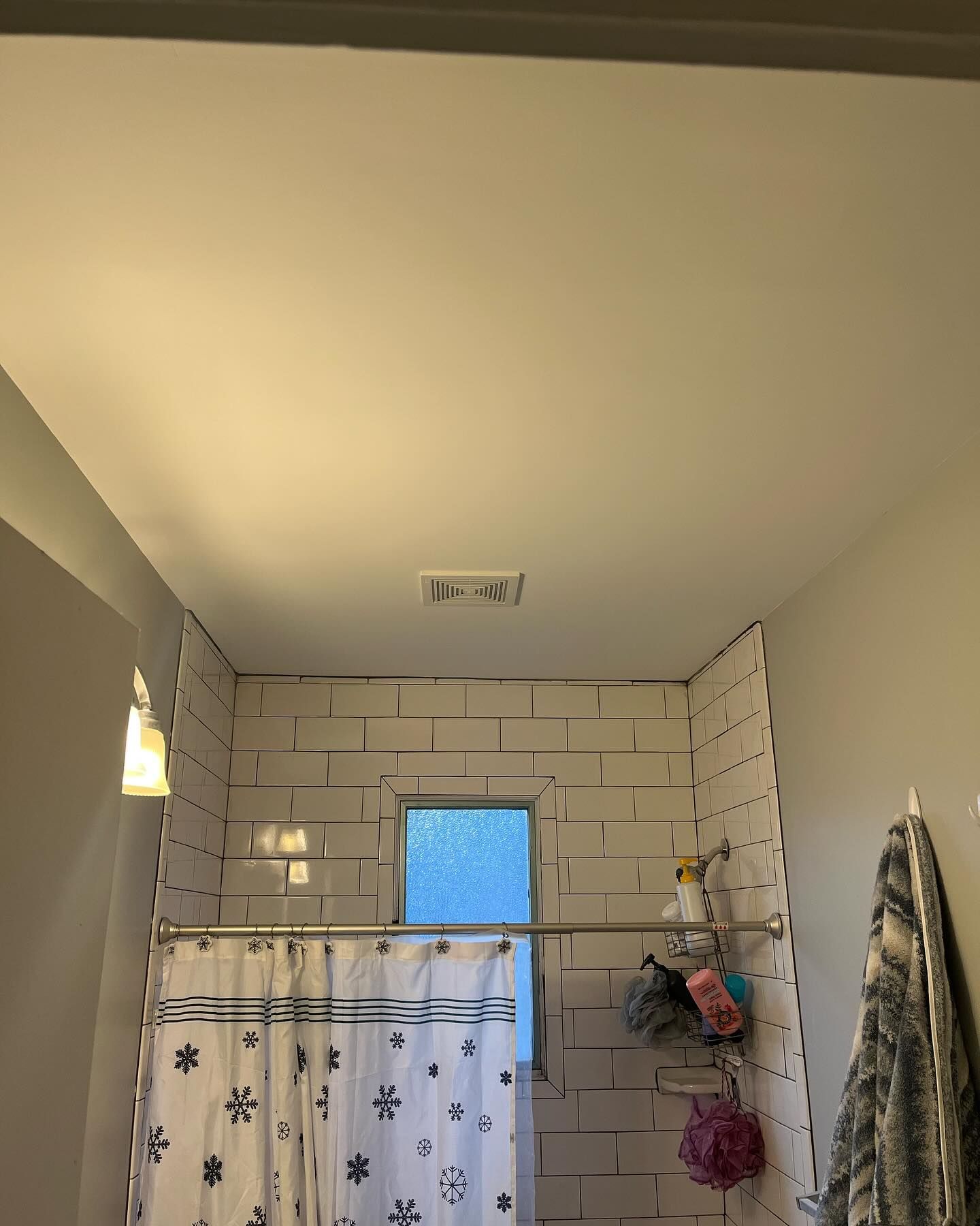 Bathroom with white tile walls, shower curtain, and a window.