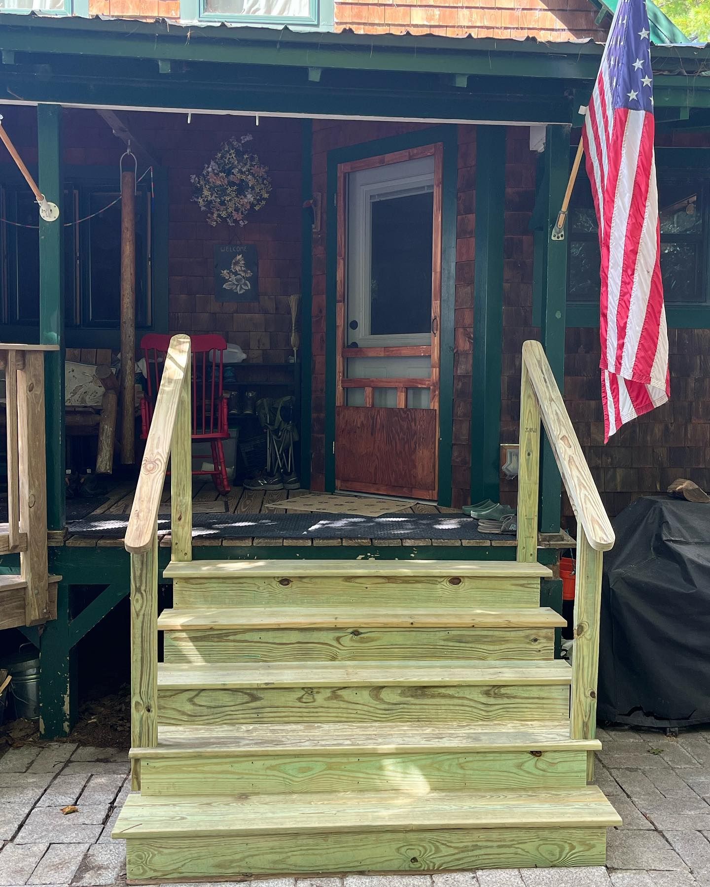 Wooden steps leading to a cabin entrance with an American flag.
