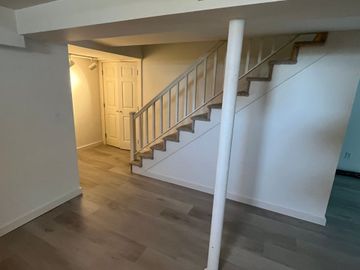 Hallway with stairs and light-colored wood paneling; cork floor.