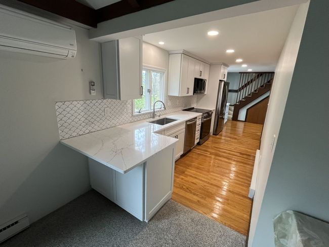 Modern kitchen with white cabinets, countertops, and appliances, featuring a folding countertop.