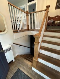 Staircase with wooden steps and white railing leading down to a lower level; doorway visible below.
