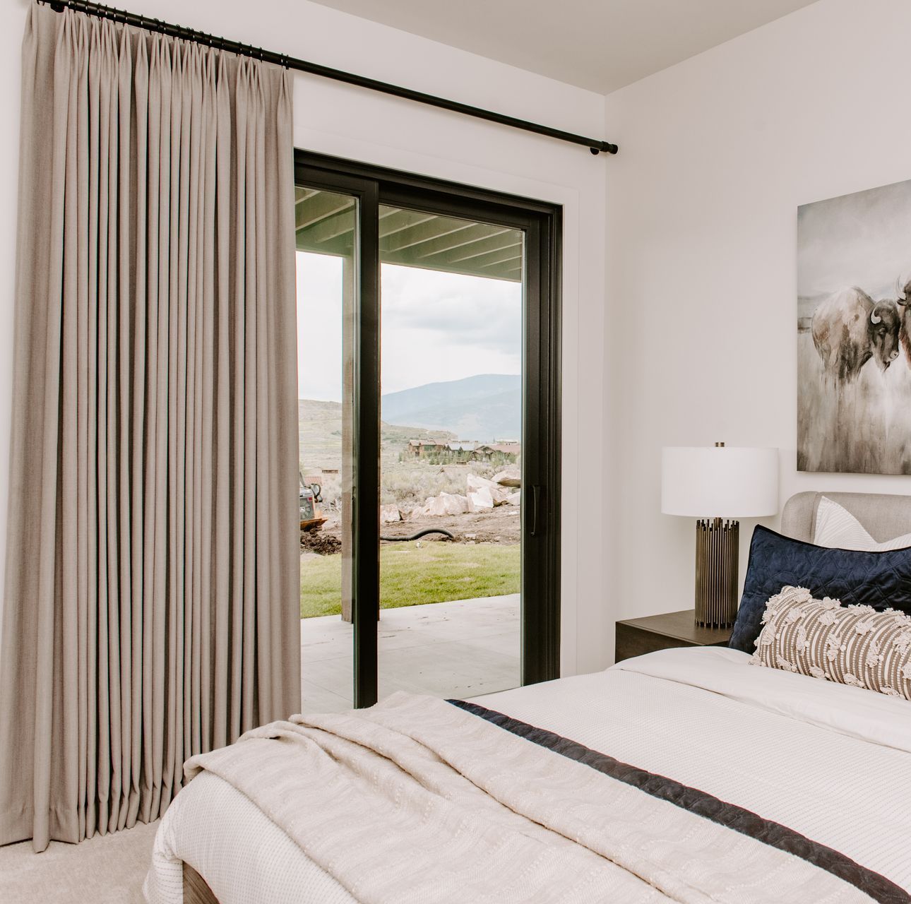 Custom drapery and roller shades in luxury bedroom with scenic views