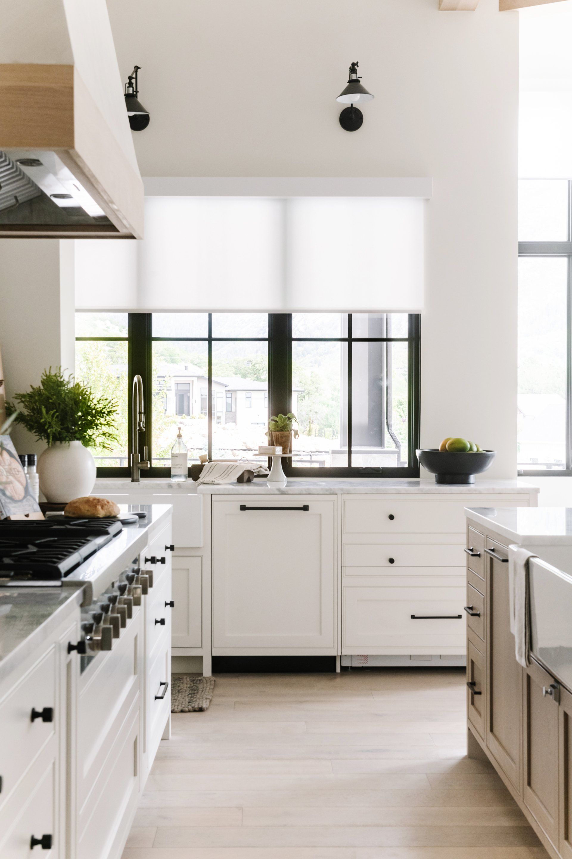 White motorized roller shade covering a tall window in a modern interior with minimalist wall lighting