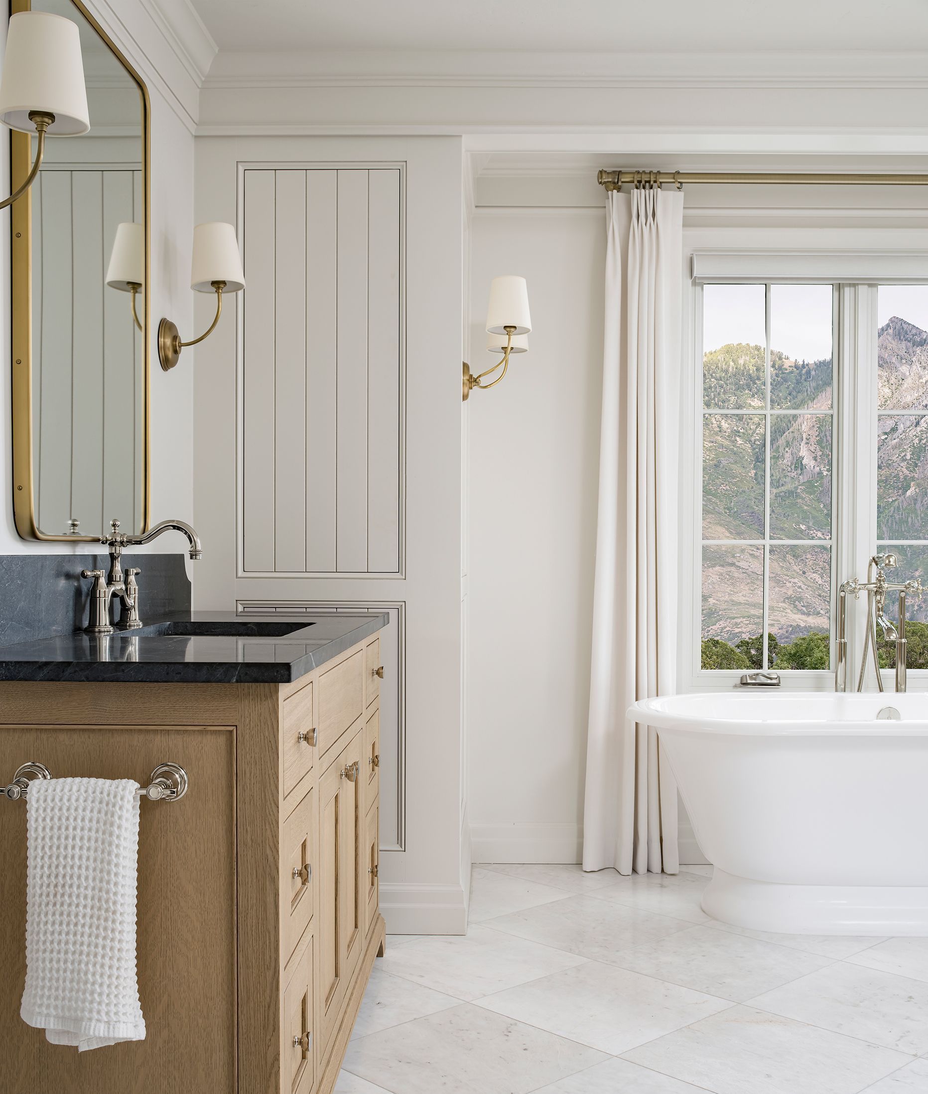 Bathroom window with custom drapery panels, brass hardware, and scenic mountain views