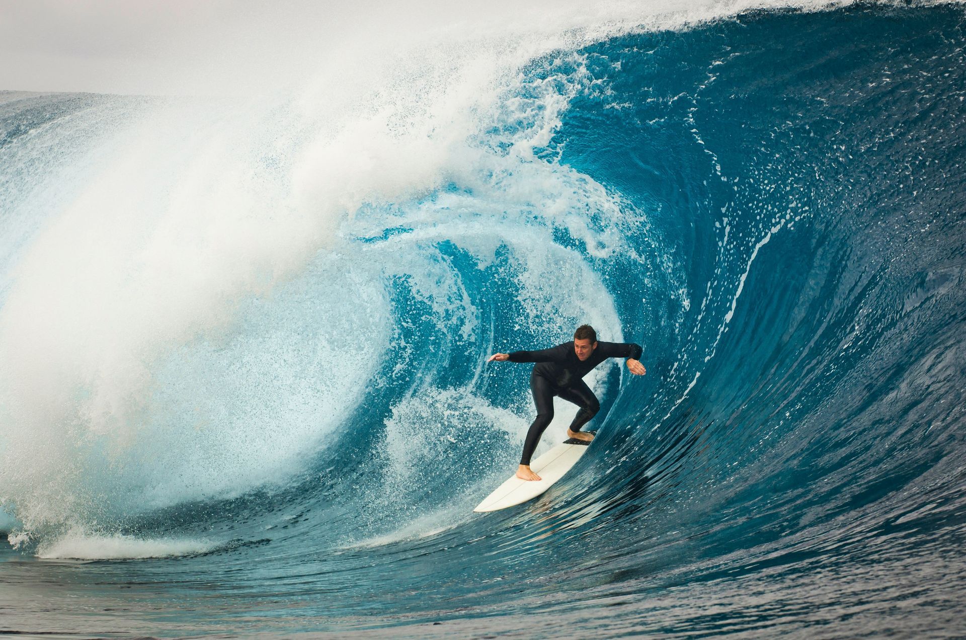 Surfer riding a large blue wave near the shore