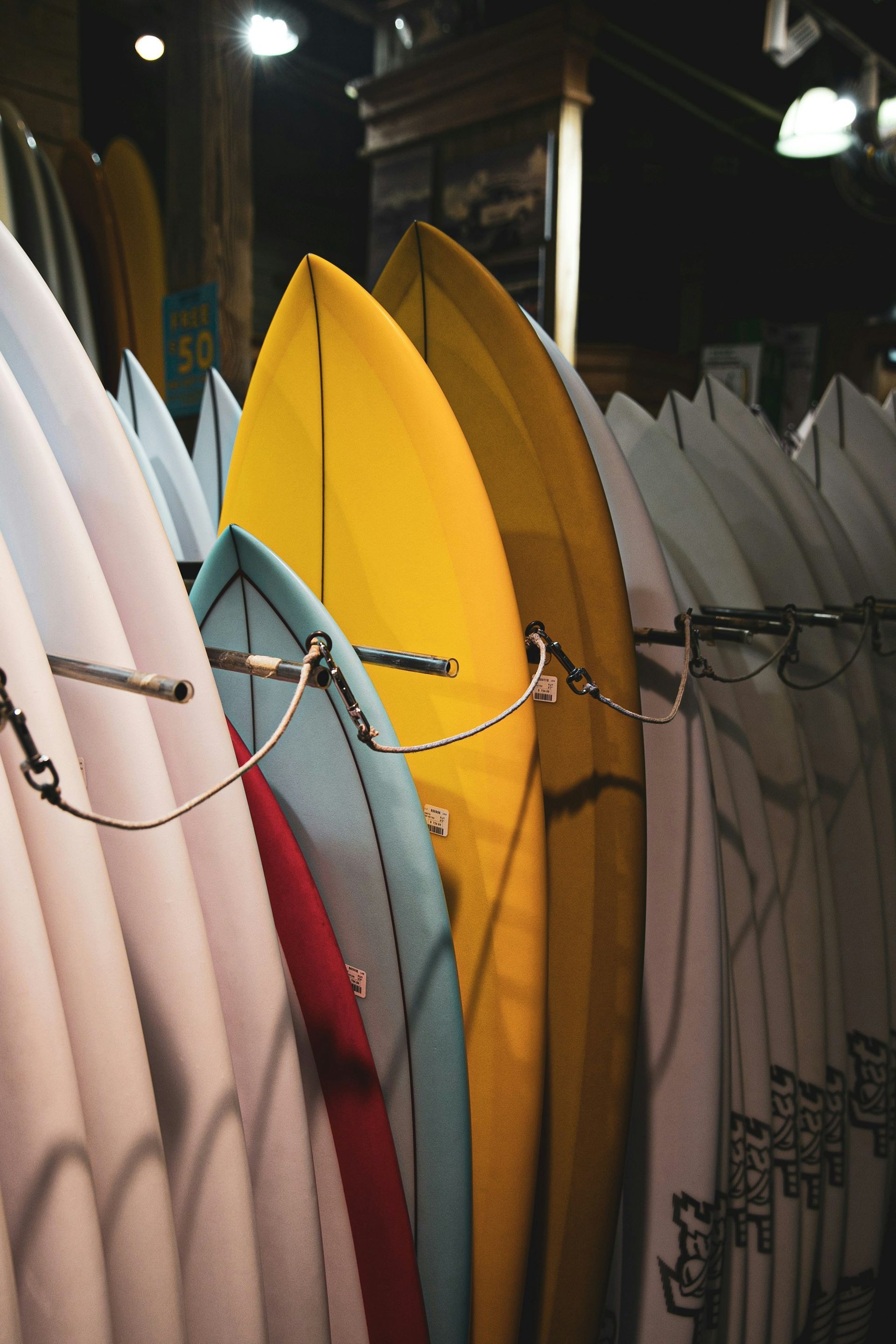 Surfboards lined up vertically at night, including a bright yellow board in the center.