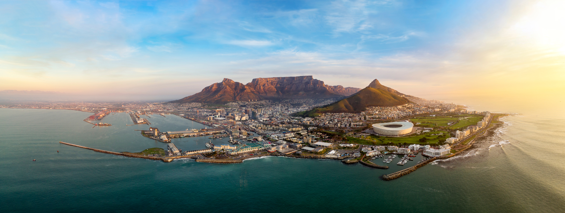 Aerial view of Cape Town, South Africa, with Table Mountain in the background and the ocean in the foreground.