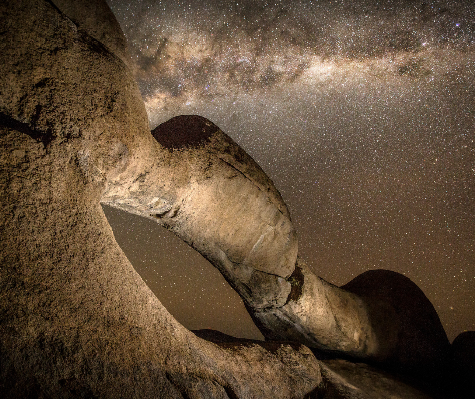 Rock arch silhouetted against a starry night sky and Milky Way.