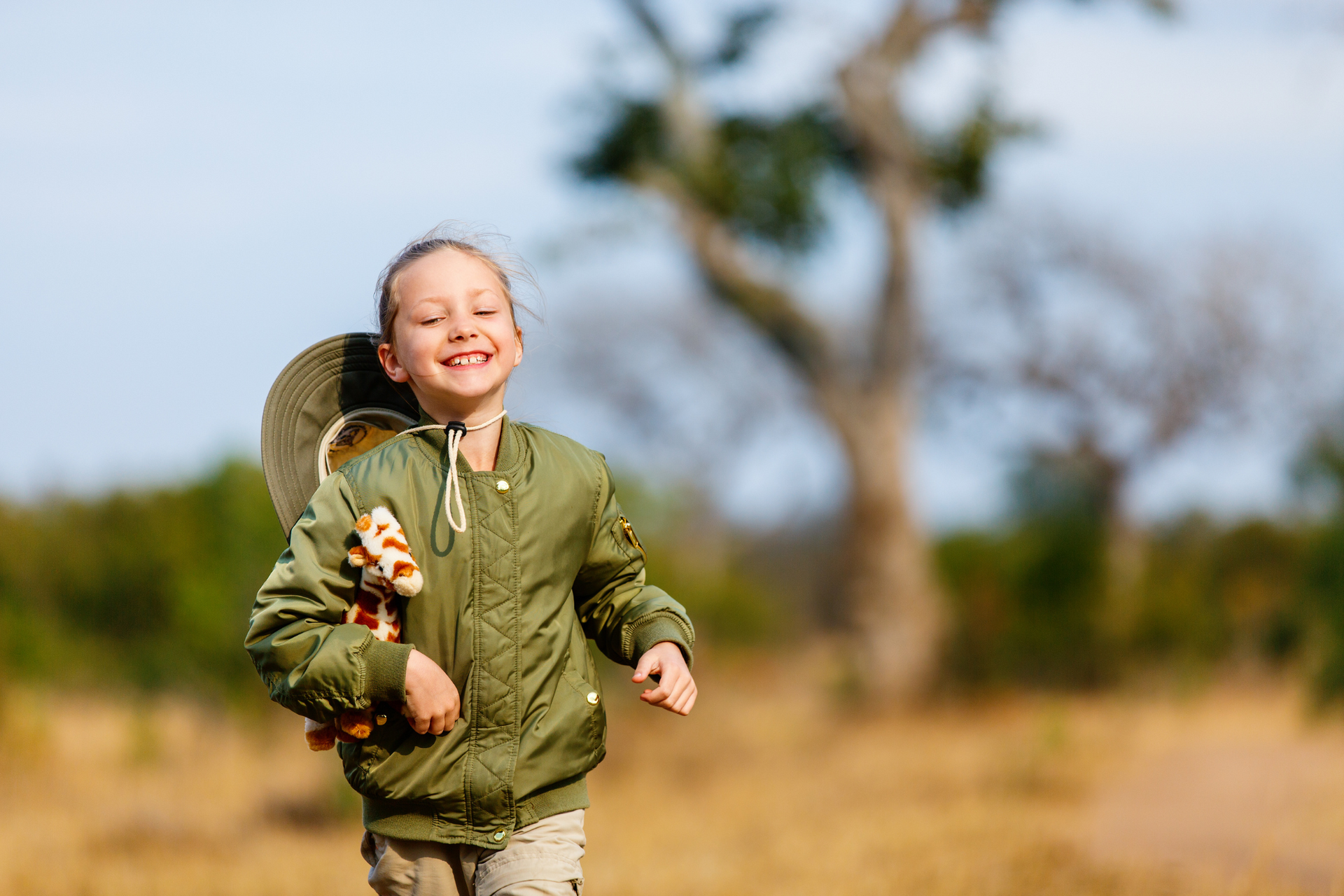 A little girl is running in a field with a stuffed animal on her back. Family Friendly Safari