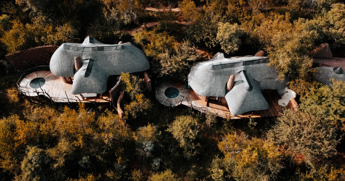 Two small white dome houses on round platforms amid dense autumn foliage