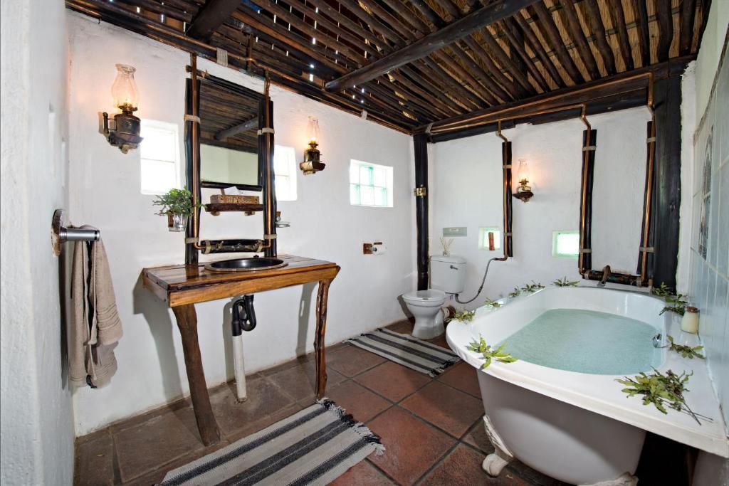 Bathroom with white walls, bamboo ceiling, wooden vanity, and clawfoot bathtub.