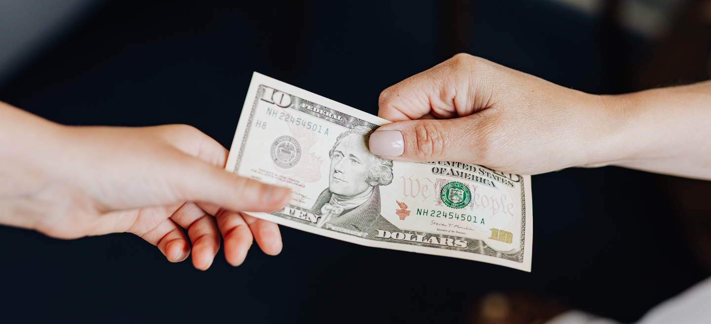 A person is handing another person a dollar bill.