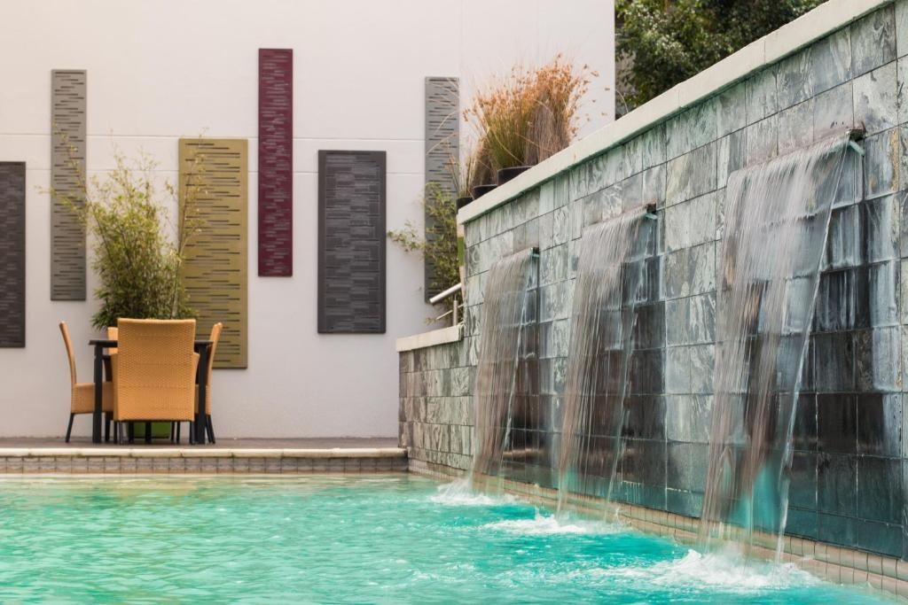 Swimming pool with waterfall feature and outdoor seating area.