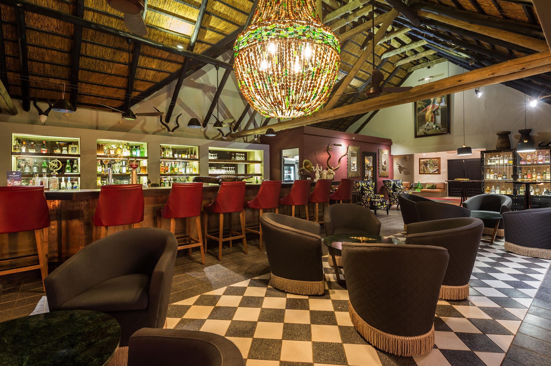 A restaurant with a checkered floor , chairs , tables and a bar.