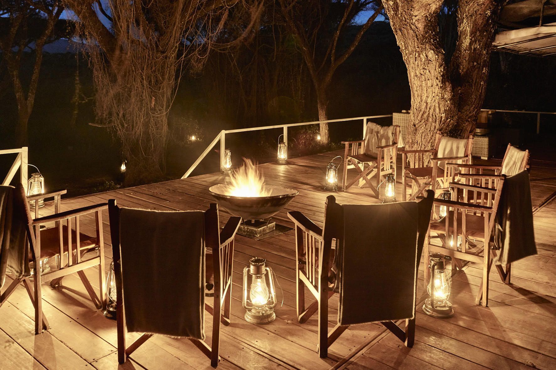 A wooden deck with chairs and lanterns and a fire pit Ngorongoro Crater