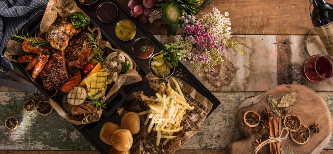 A wooden table topped with plates of food and wine glasses.