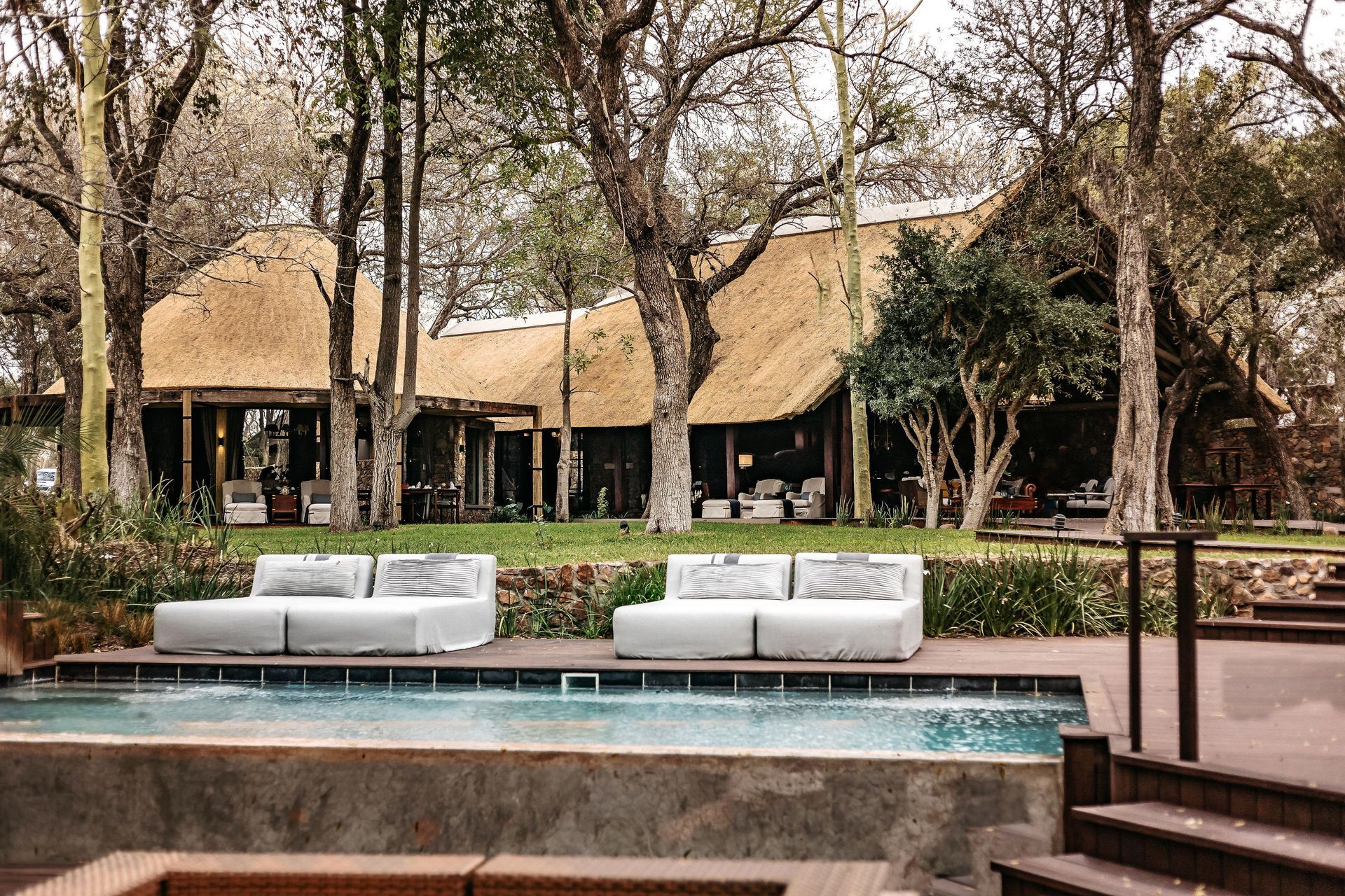 A large swimming pool in front of a thatched building