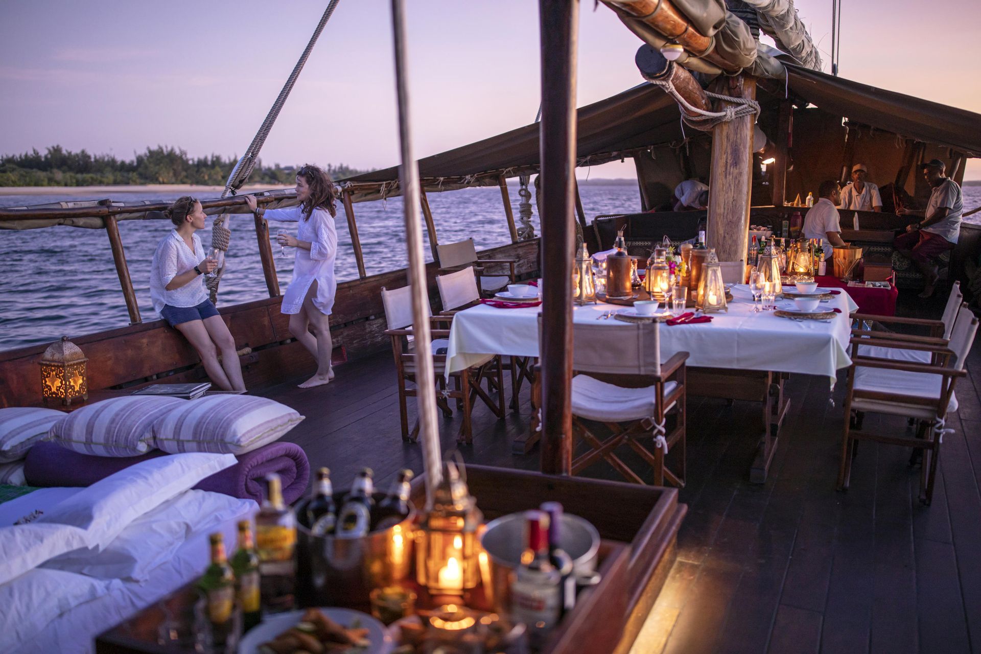 Two women are sitting on the deck of a boat with a table and chairs.