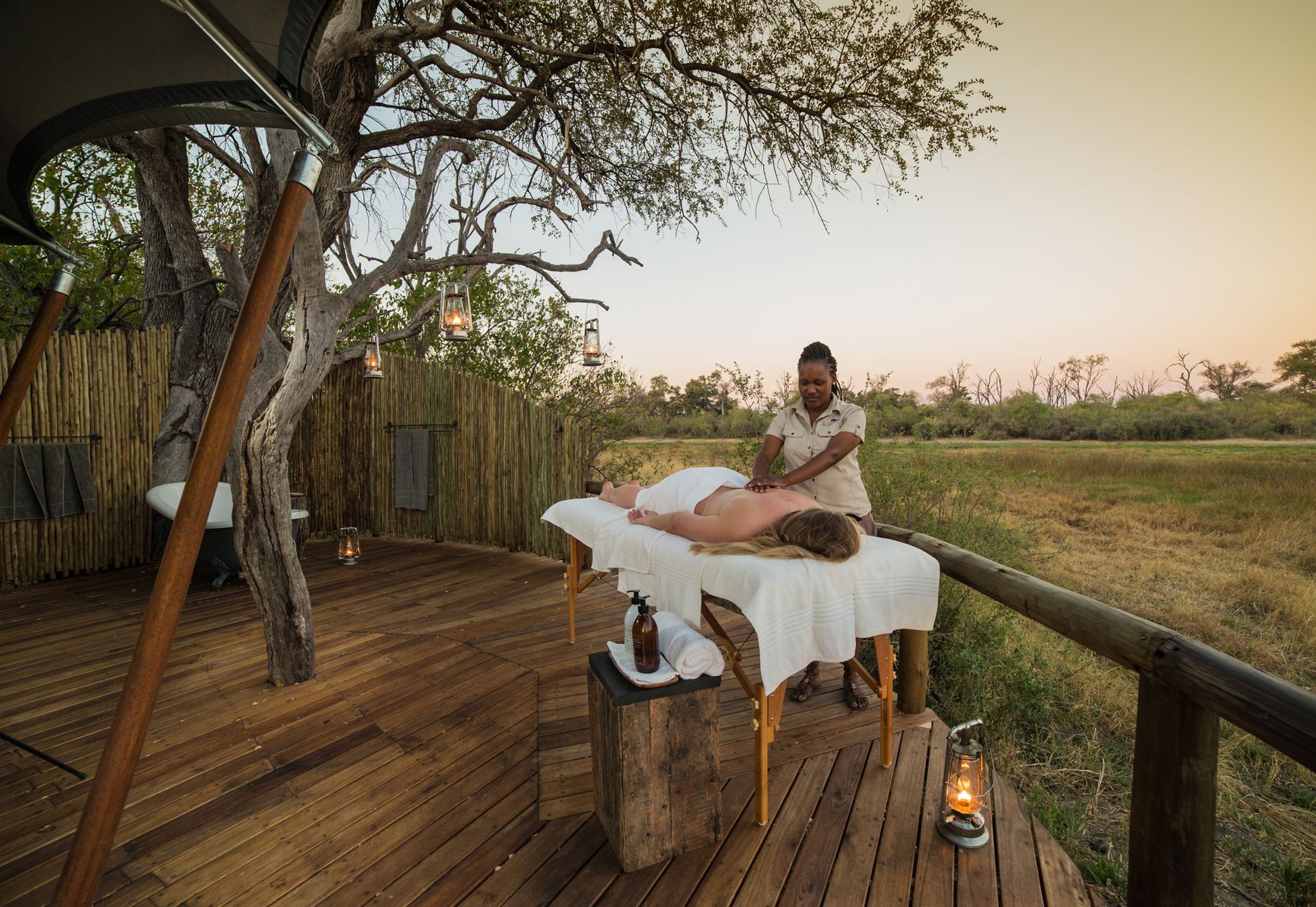 Woman receiving massage outdoors on wooden deck.