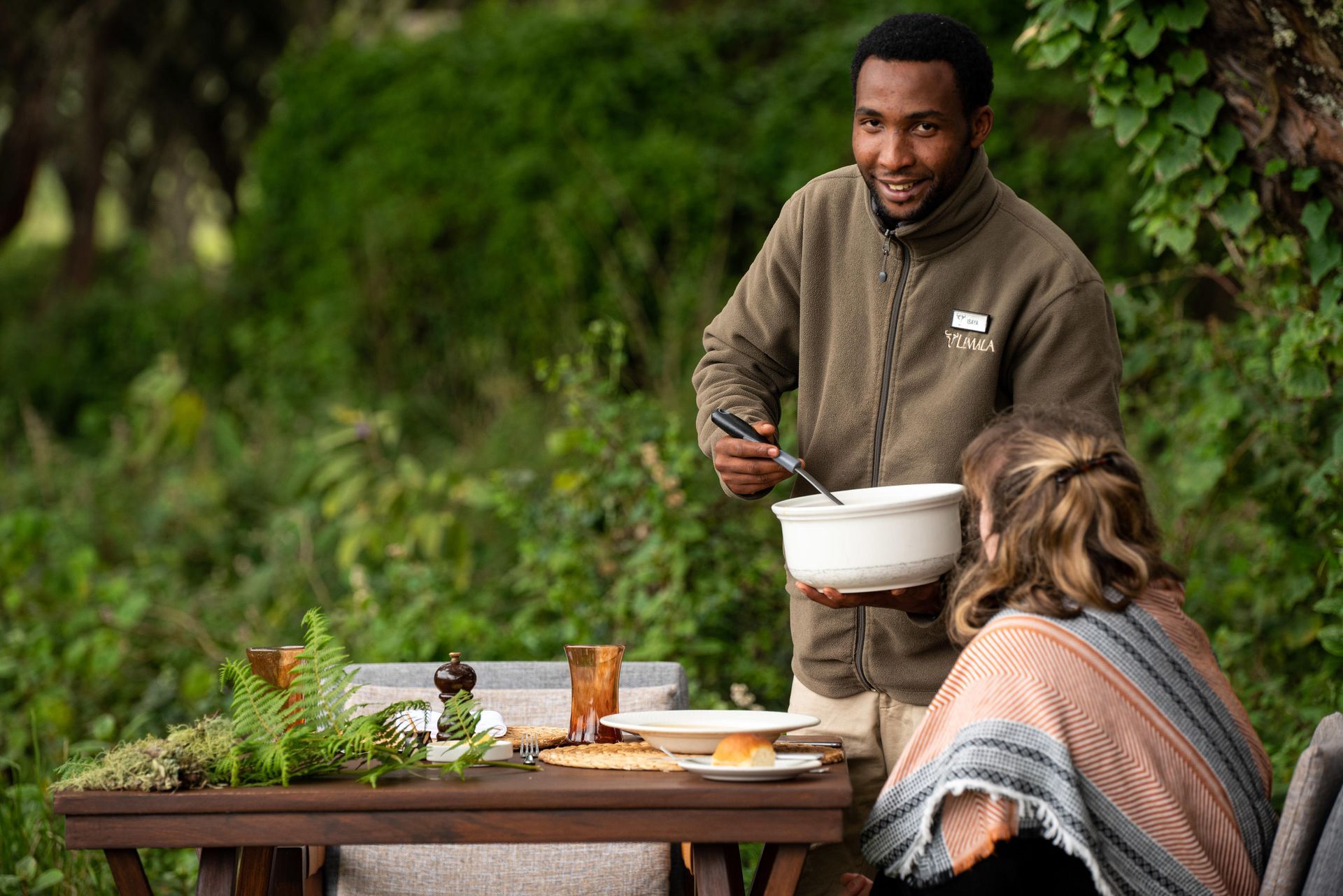 A man is serving food to a woman at a table Ngorongoro Crater