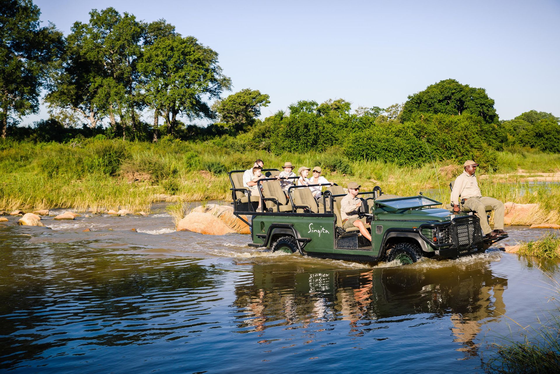 A group of people are riding in a jeep through a river.Luxury African Safaris