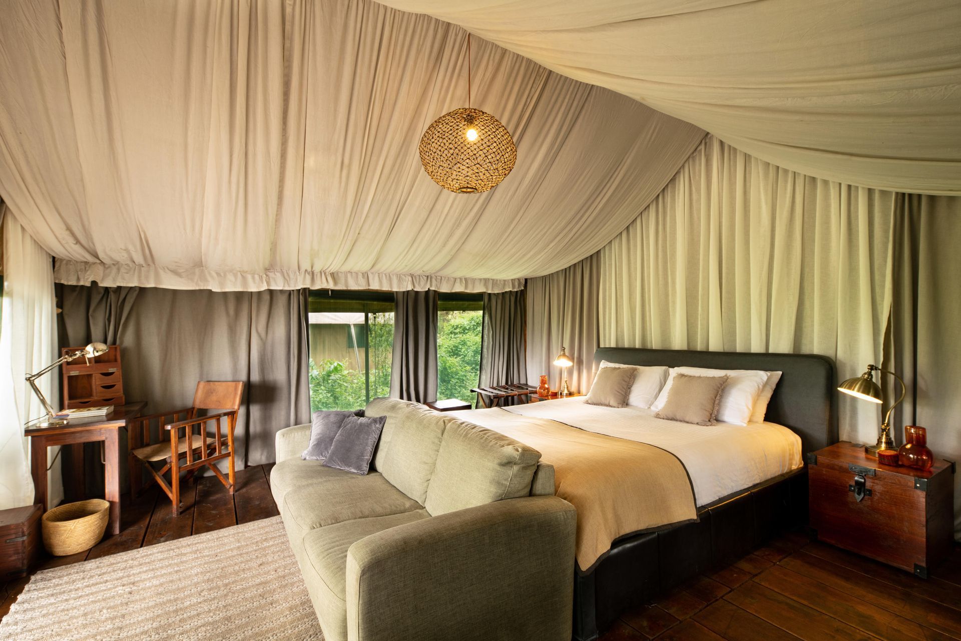 A bedroom with a couch and a bed under a tent. Ngorongoro Crater