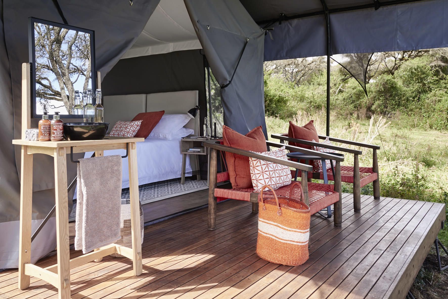 A tent with a bed and chairs on a wooden deck. Ngorongoro Crater
