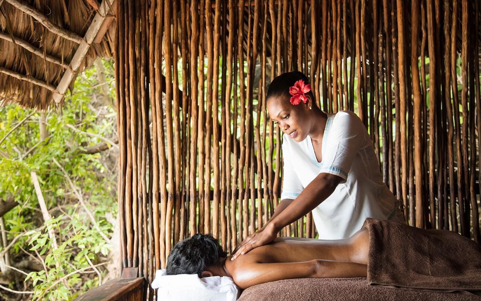 Woman giving a massage to another woman at an outdoor spa.