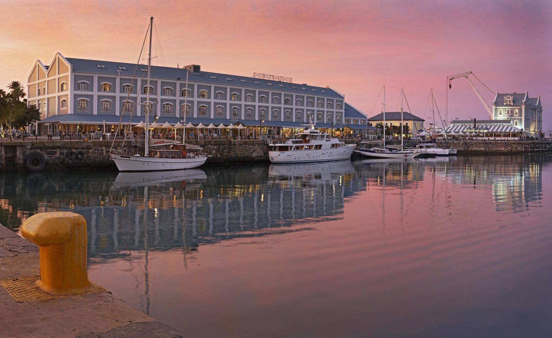 A harbor with boats docked in front of a building at sunset.