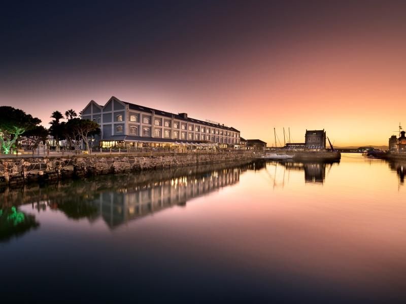 Harbor at sunset with a waterfront building and its reflection in calm water