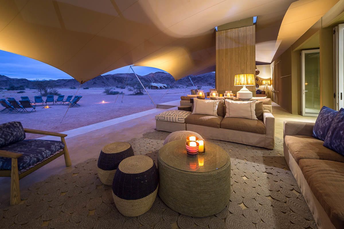 A living room with a couch , table and chairs under a tent. Namibia Safari