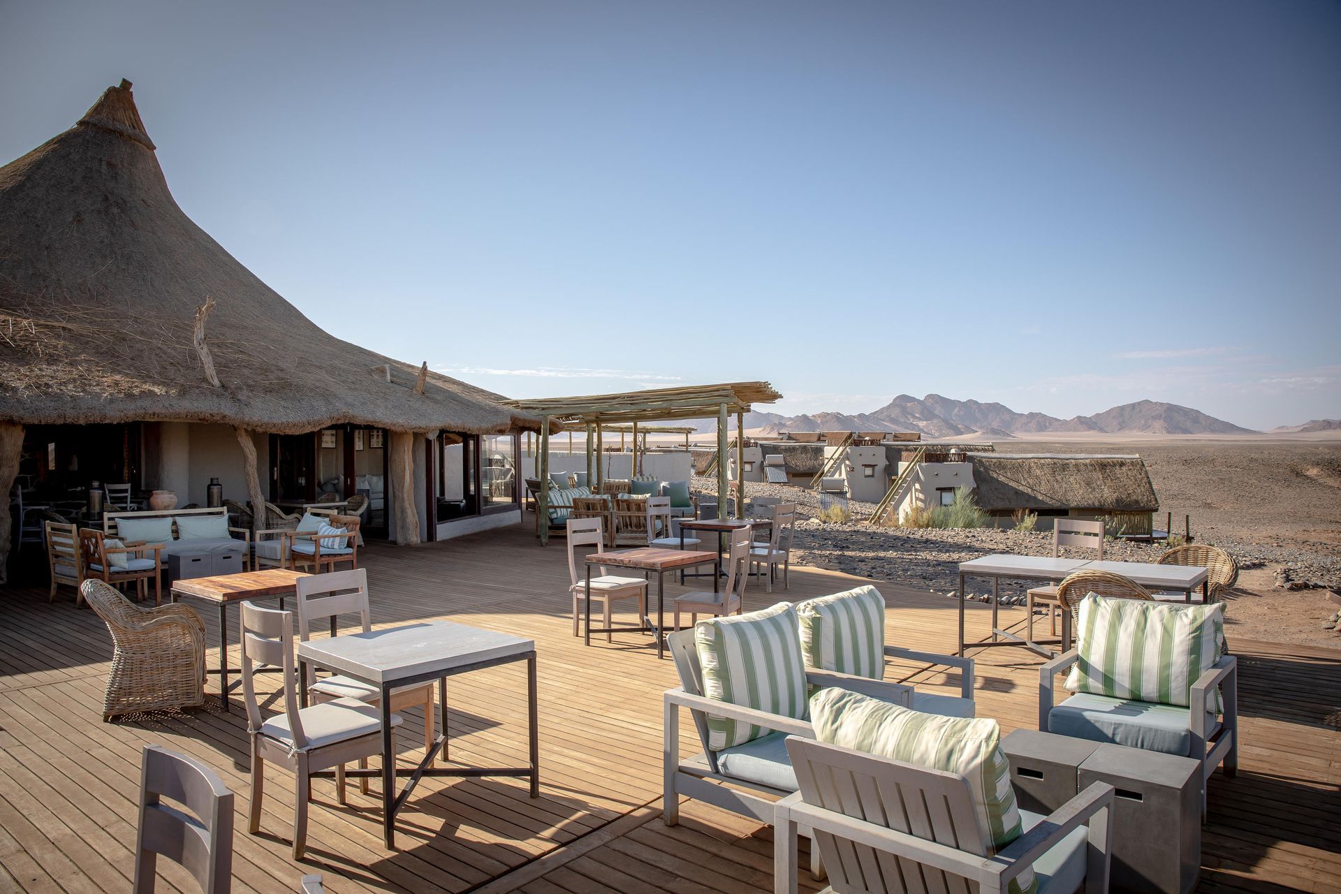 A patio with tables and chairs in the desert with mountains in the background. Namibia Safari