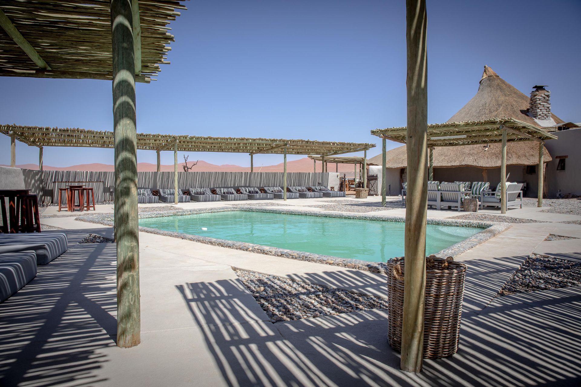 A large swimming pool with a thatched hut in the background