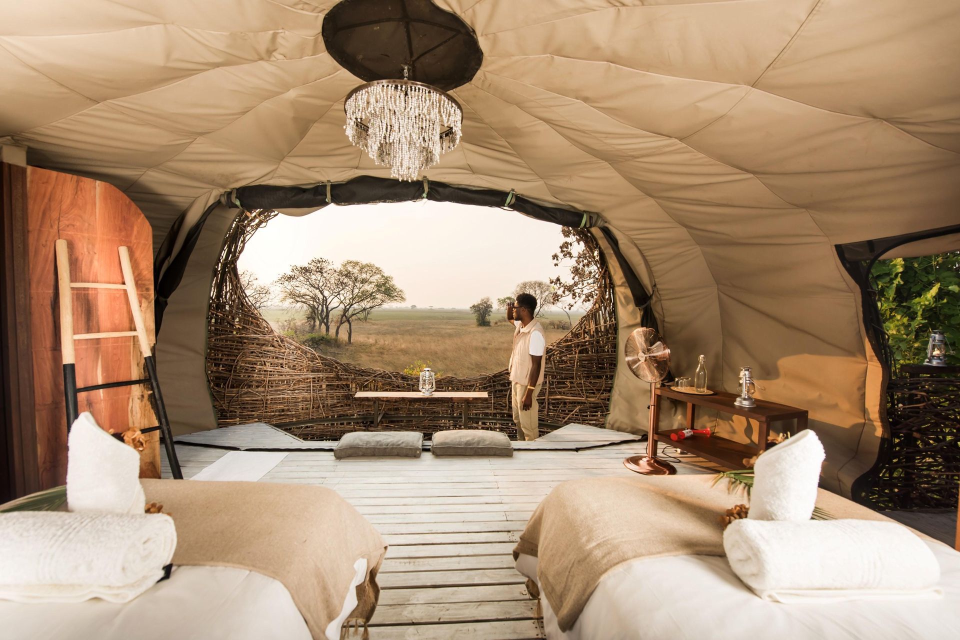 A woman is standing in a tent with two beds.