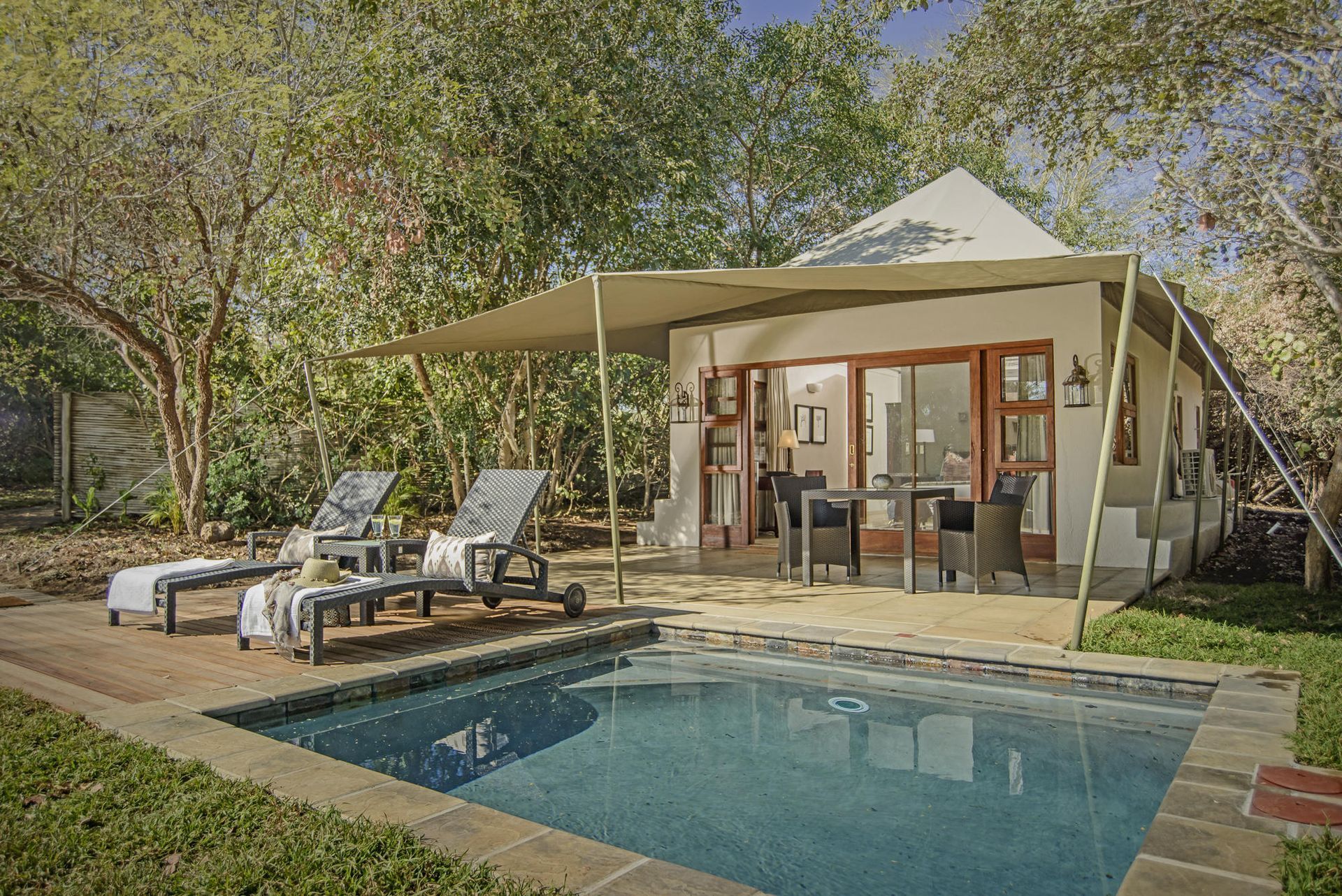 A private pool with a patio, chairs, and an outdoor dining area at a luxury lodge.
