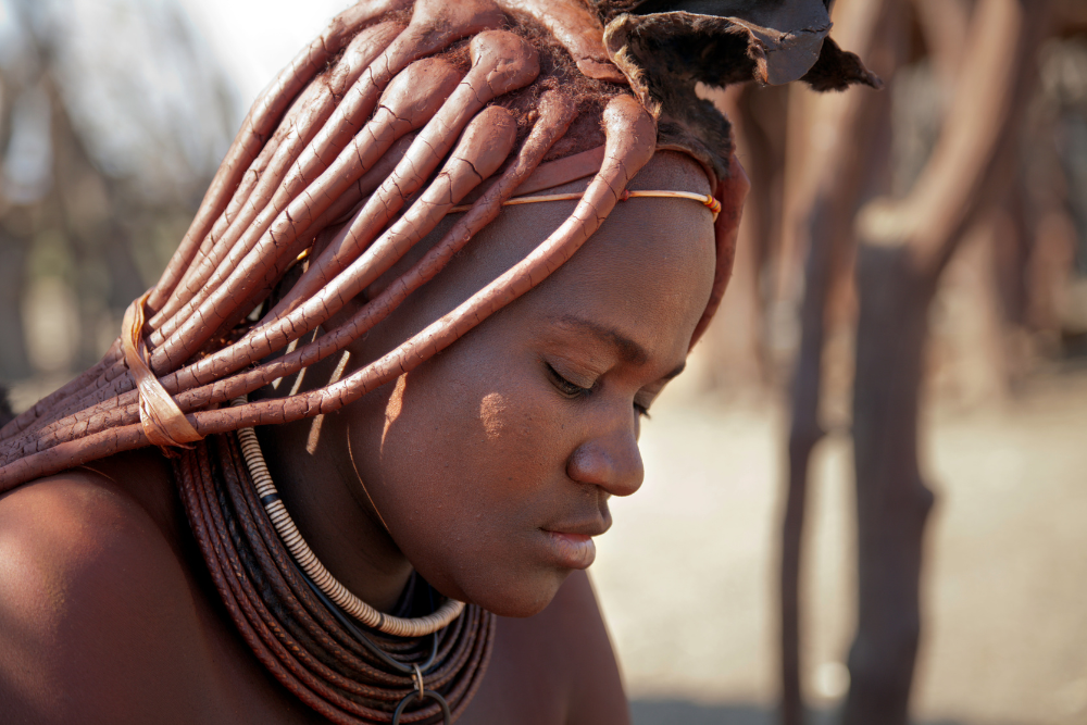 A woman with dreadlocks is wearing a necklace and has her eyes closed