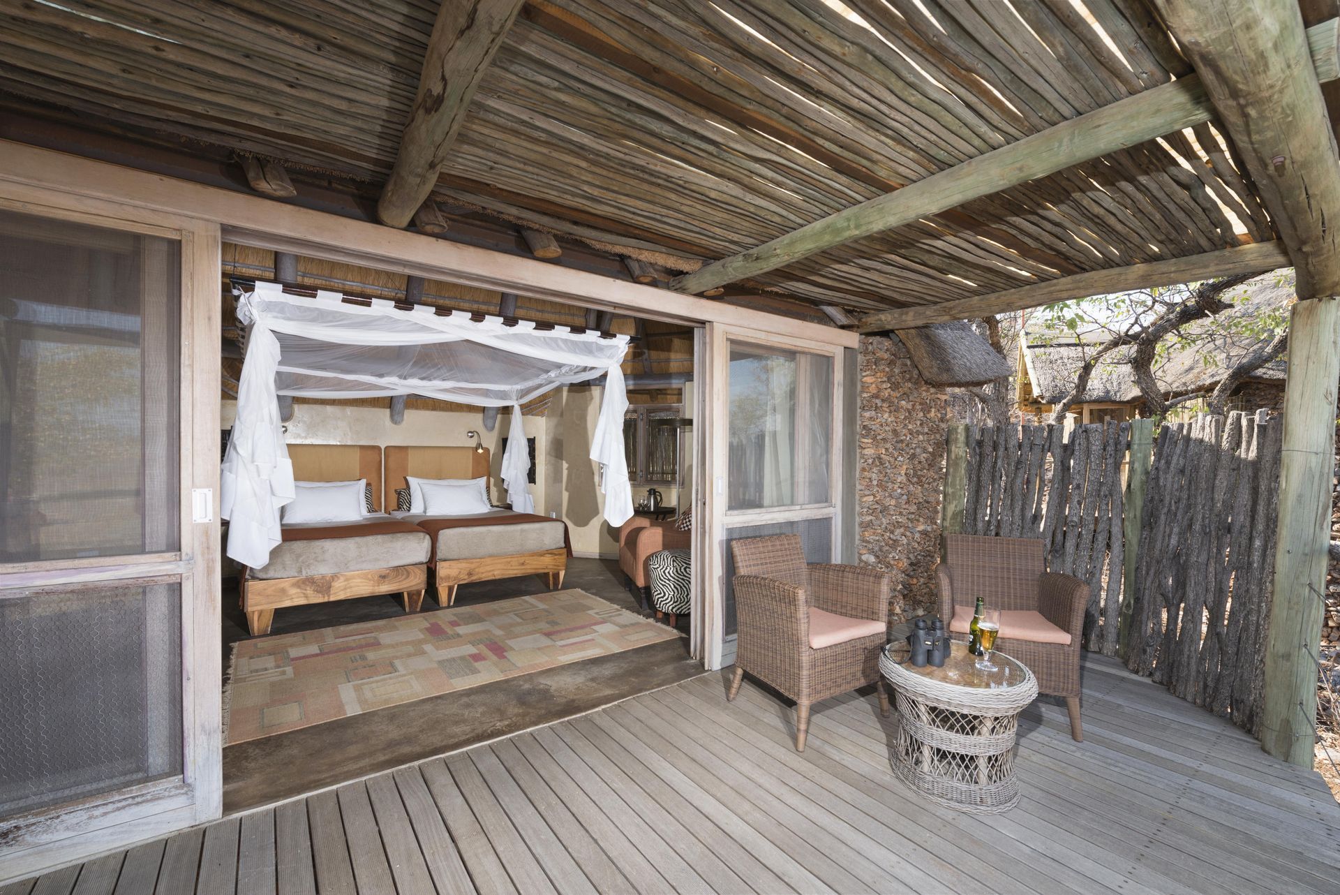 A bedroom with a canopy bed and a wooden deck with chairs and a table. Namibia Safari