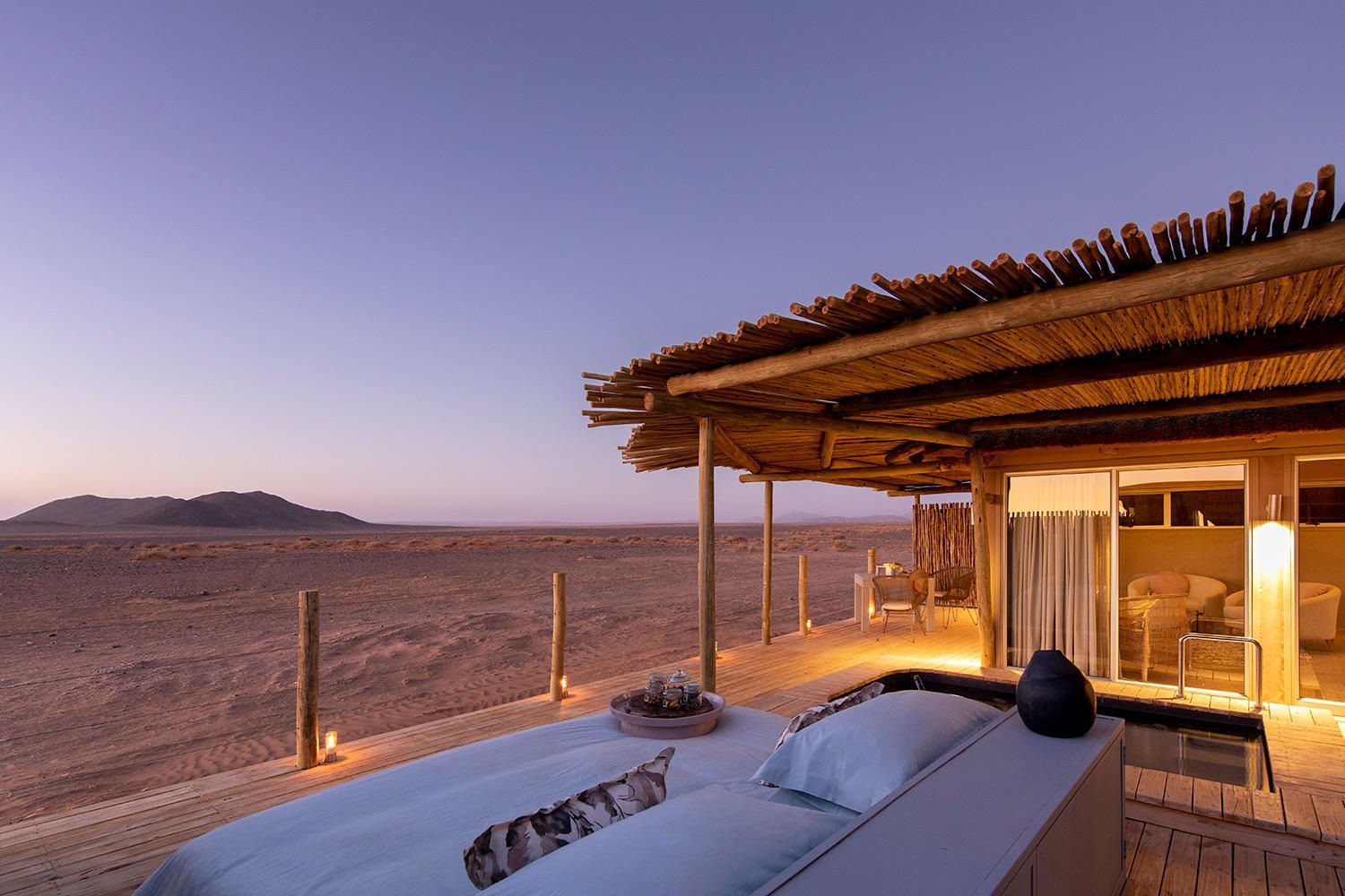 A bed in front of a house with a thatched roof Namibia Safari