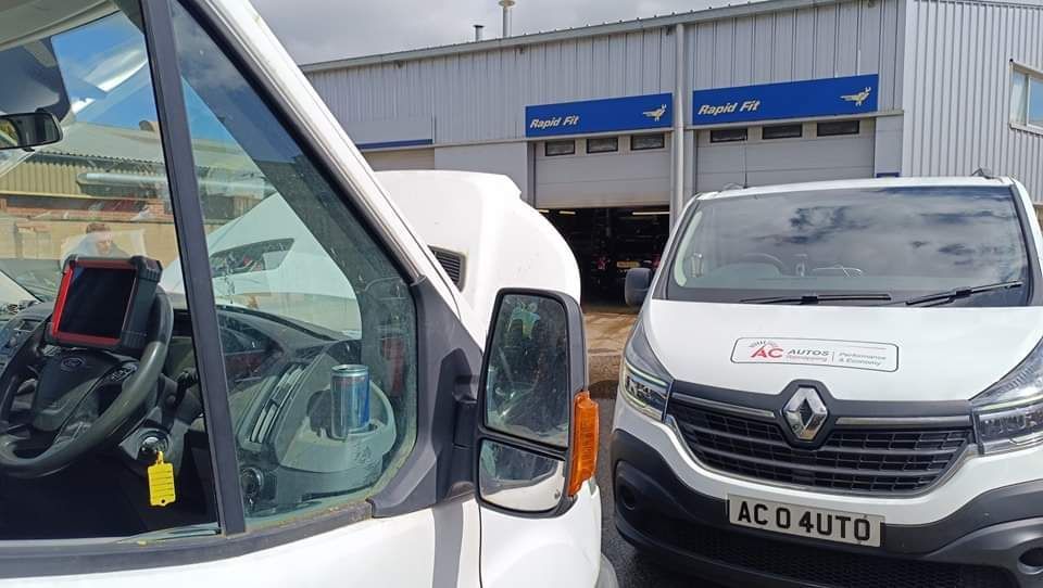 Two white vans are parked in front of a building.