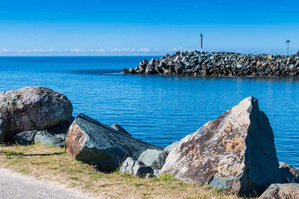 A Large Rock Sitting On The Shore Of A Body Of Water — Todd Williams Plumbing and Gas Fitting In Hallidays Point, NSW