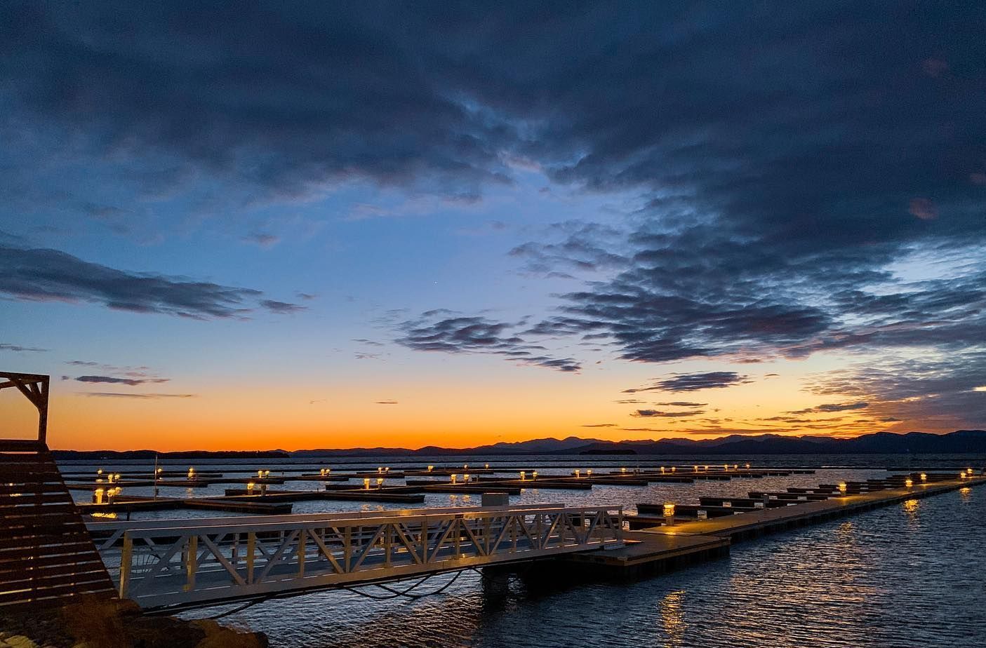 Floating docks with lights glowing at dusk under a dramatic blue and orange sky