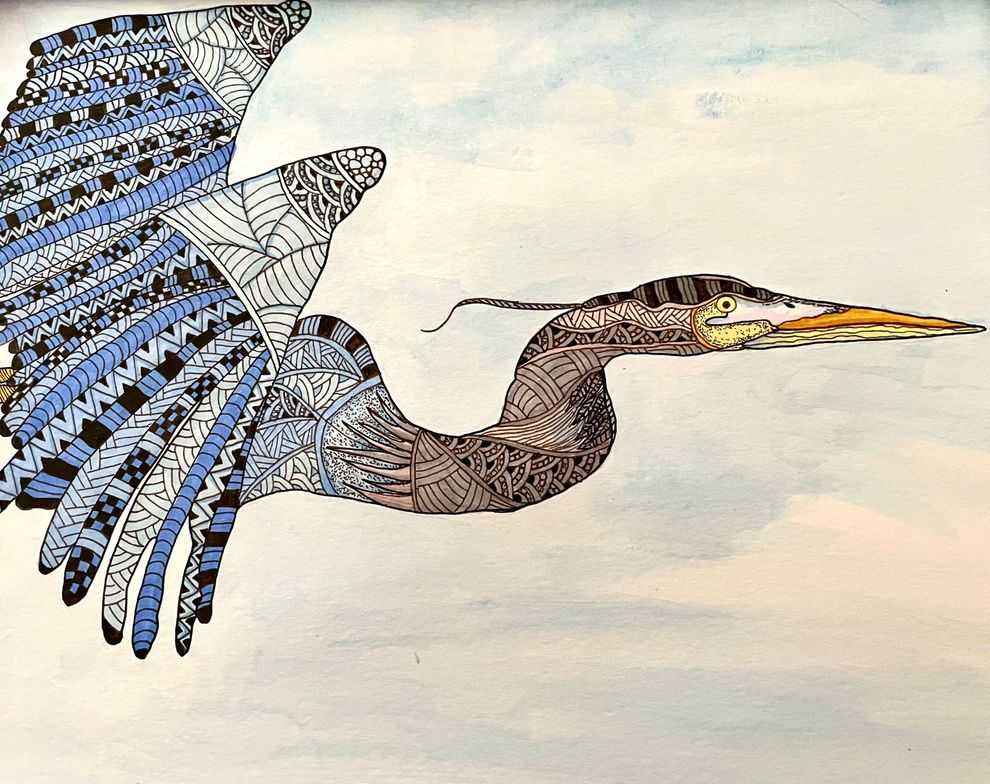 A heron with detailed patterns in flight, wings spread against a cloudy blue sky.