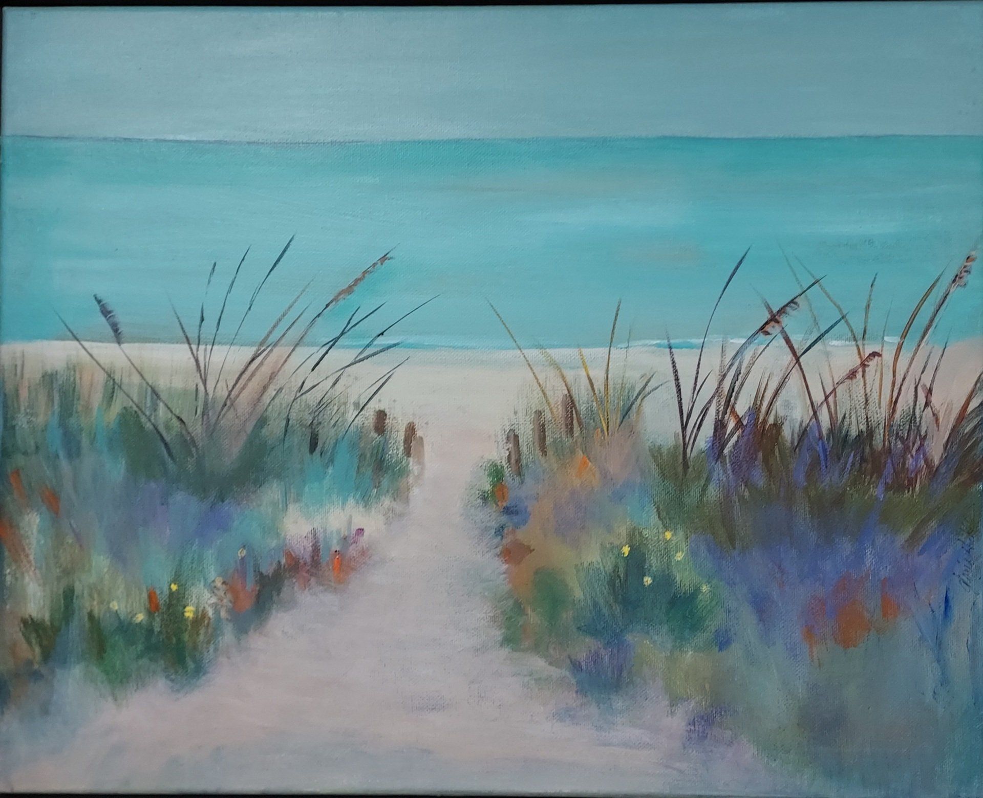 Beach path, framed by tall grasses, leads to a turquoise sea.