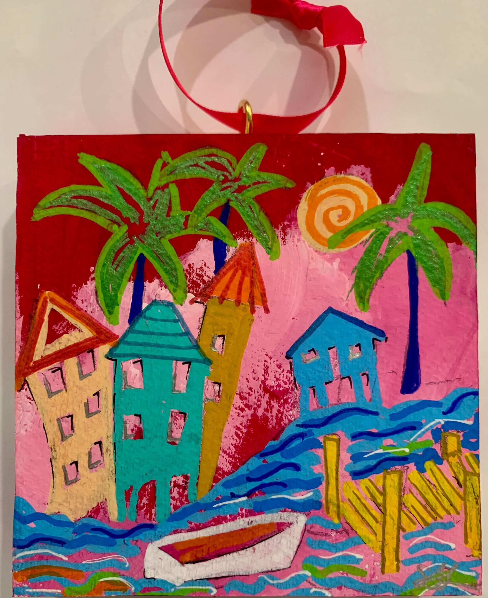 Colorful beach art: Houses, palm trees, and boat by the water with a red sky, and a hanging ribbon.
