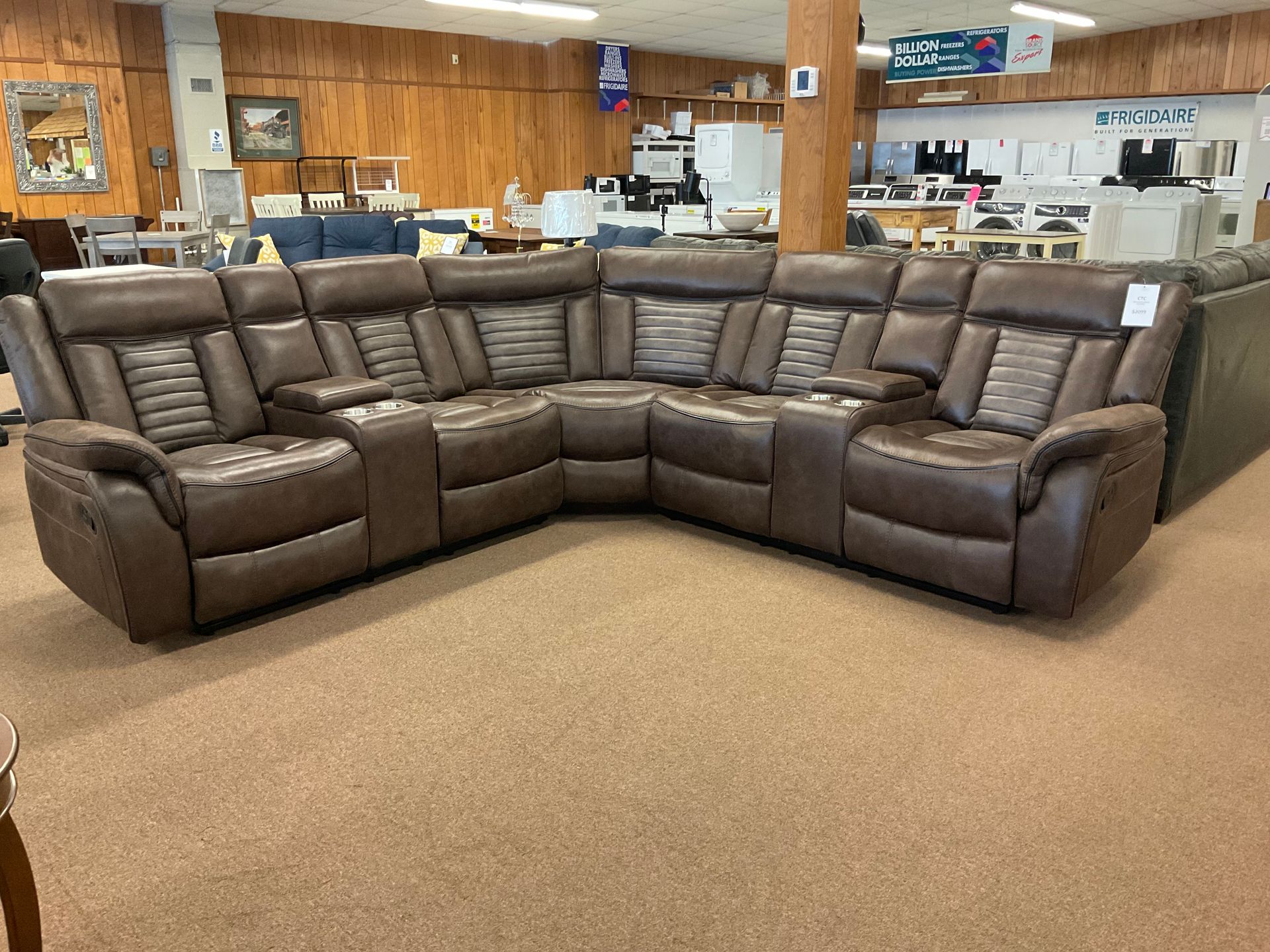 Brown leather sectional sofa with cup holders in a furniture store.