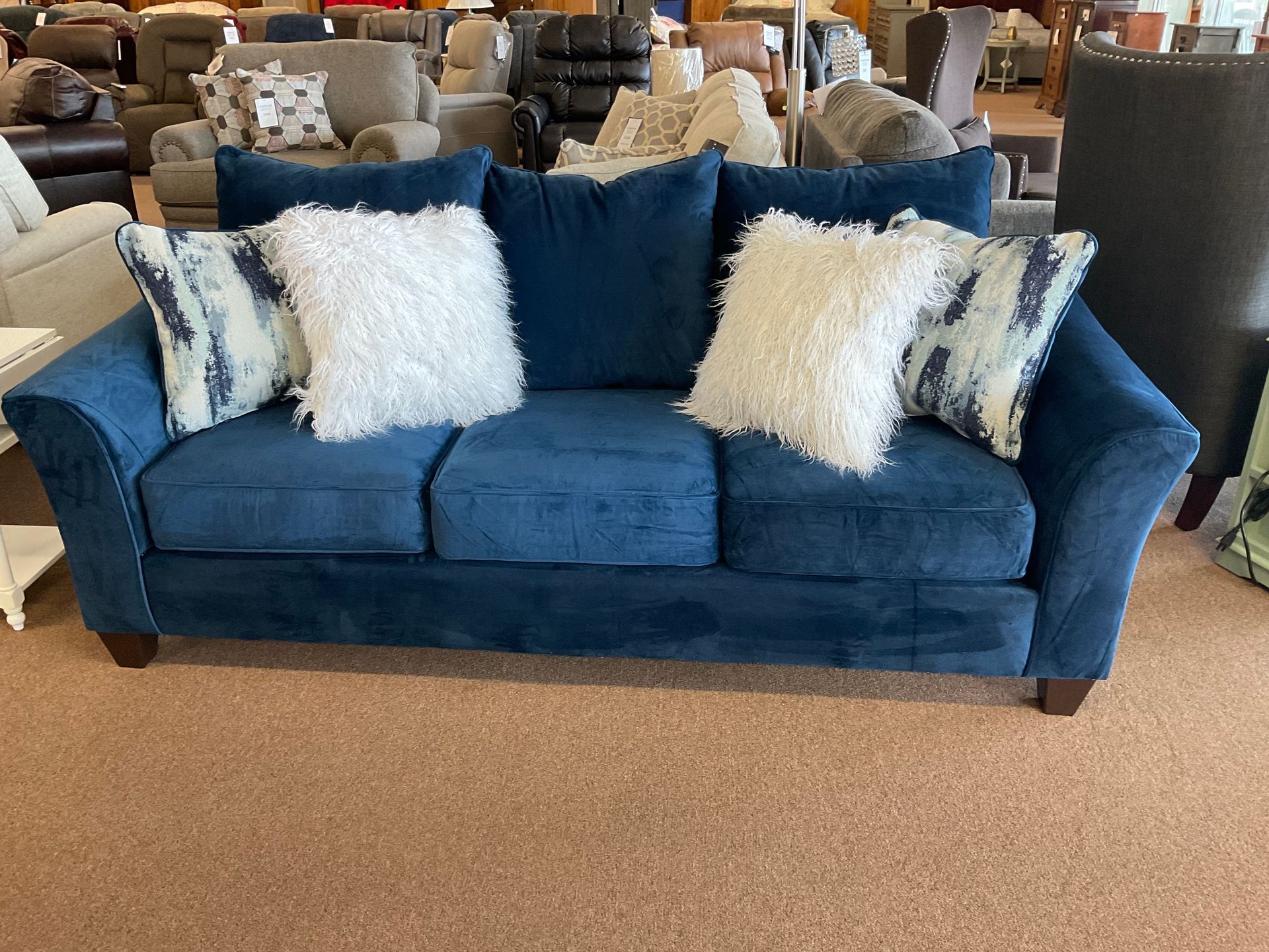 Blue sofa with fluffy white and patterned pillows in a furniture store.