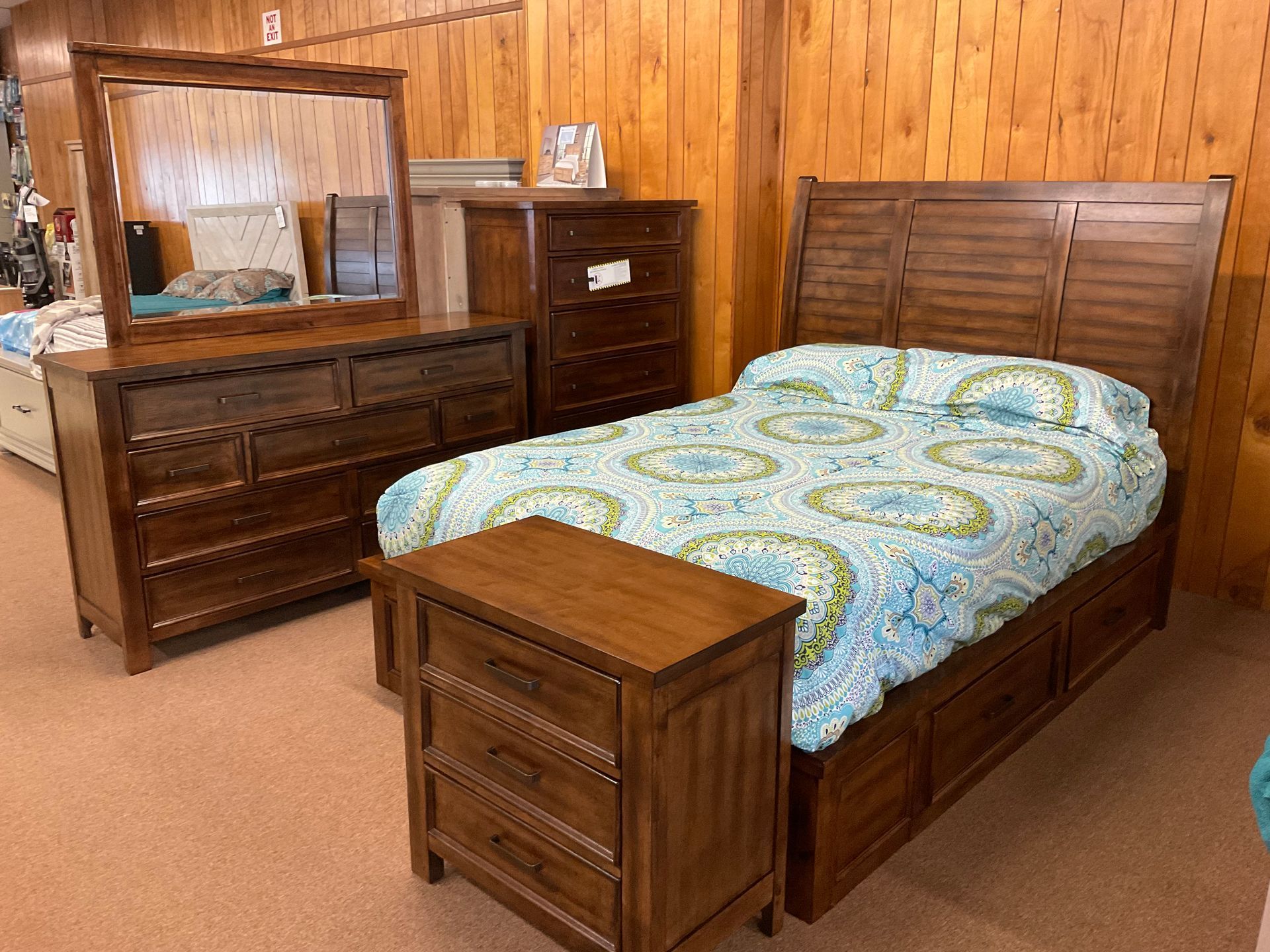 Bedroom furniture set: bed, dresser, mirror, chest, nightstand; brown wood finish, floral bedding.