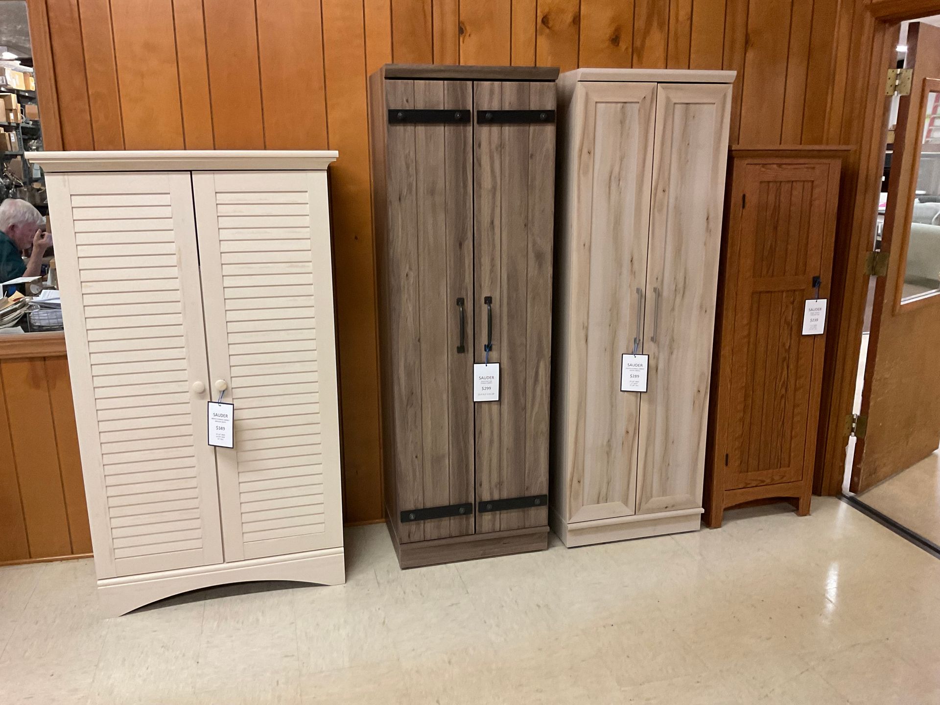 Four different colored storage cabinets against a wood paneled wall in a store.