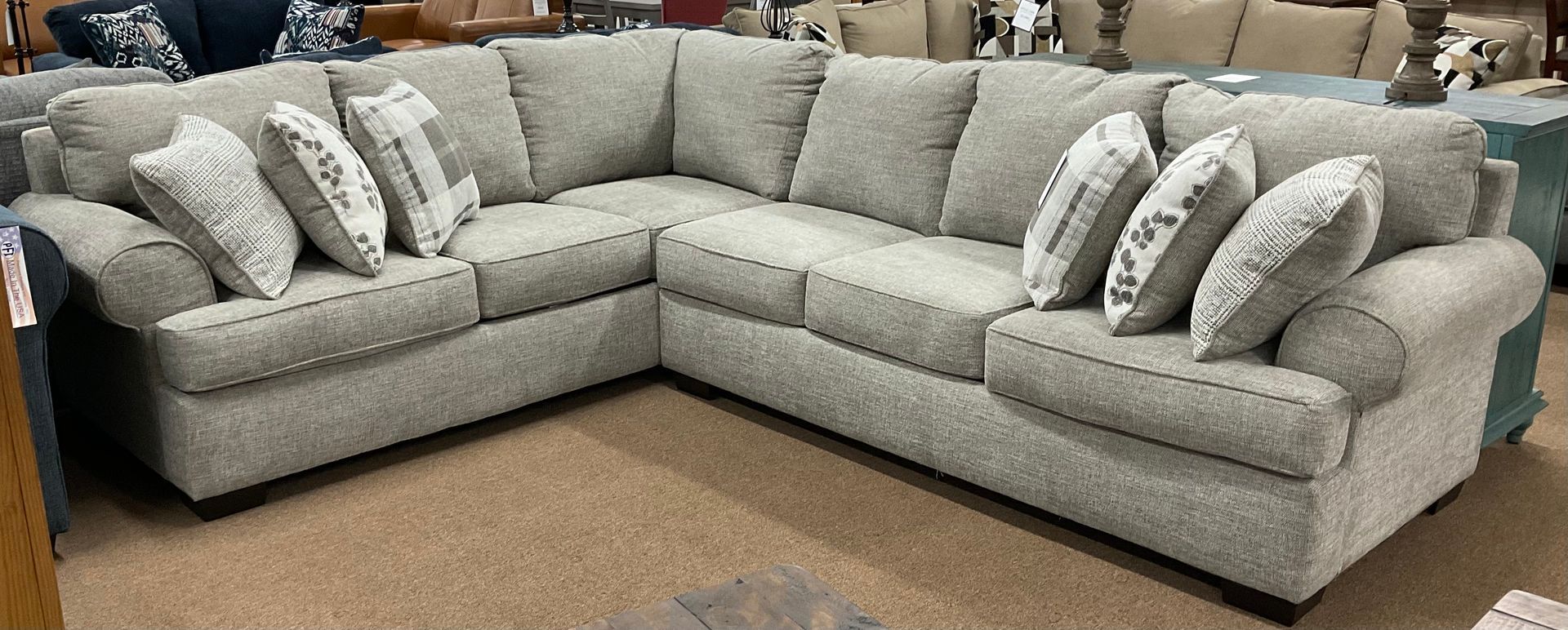 New light gray sectional sofa with several patterned throw pillows.