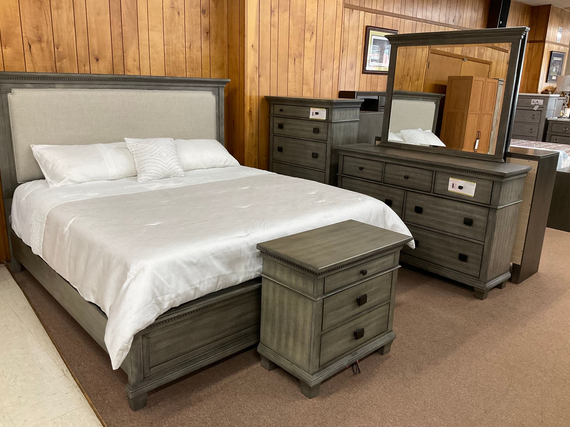 Bedroom furniture set: bed, nightstand, dresser, chest, mirror in a showroom.